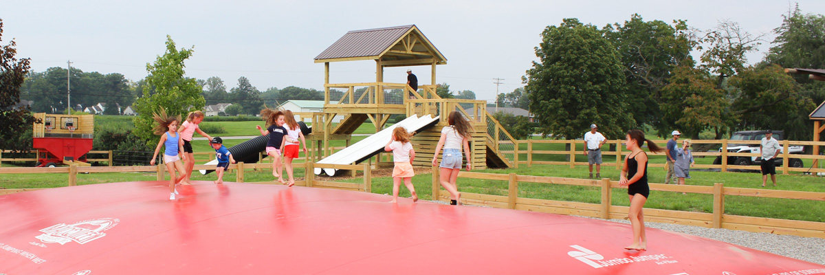 Children playing on a large red jumping pillow at MacQueen's Adventure Land