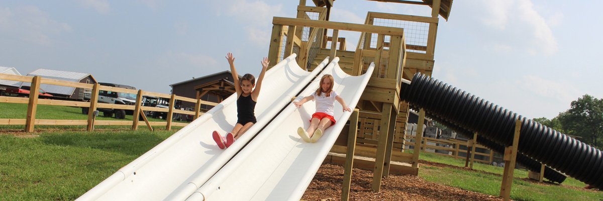 Two kids racing down slides at MacQueen's Adventure Land